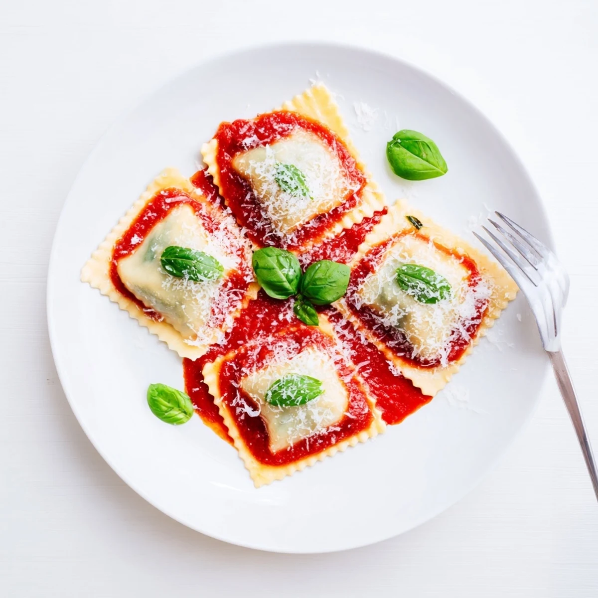 Golden-sealed spinach ricotta ravioli served on a plate of bright tomato sauce, topped with fresh basil and grated Parmesan.