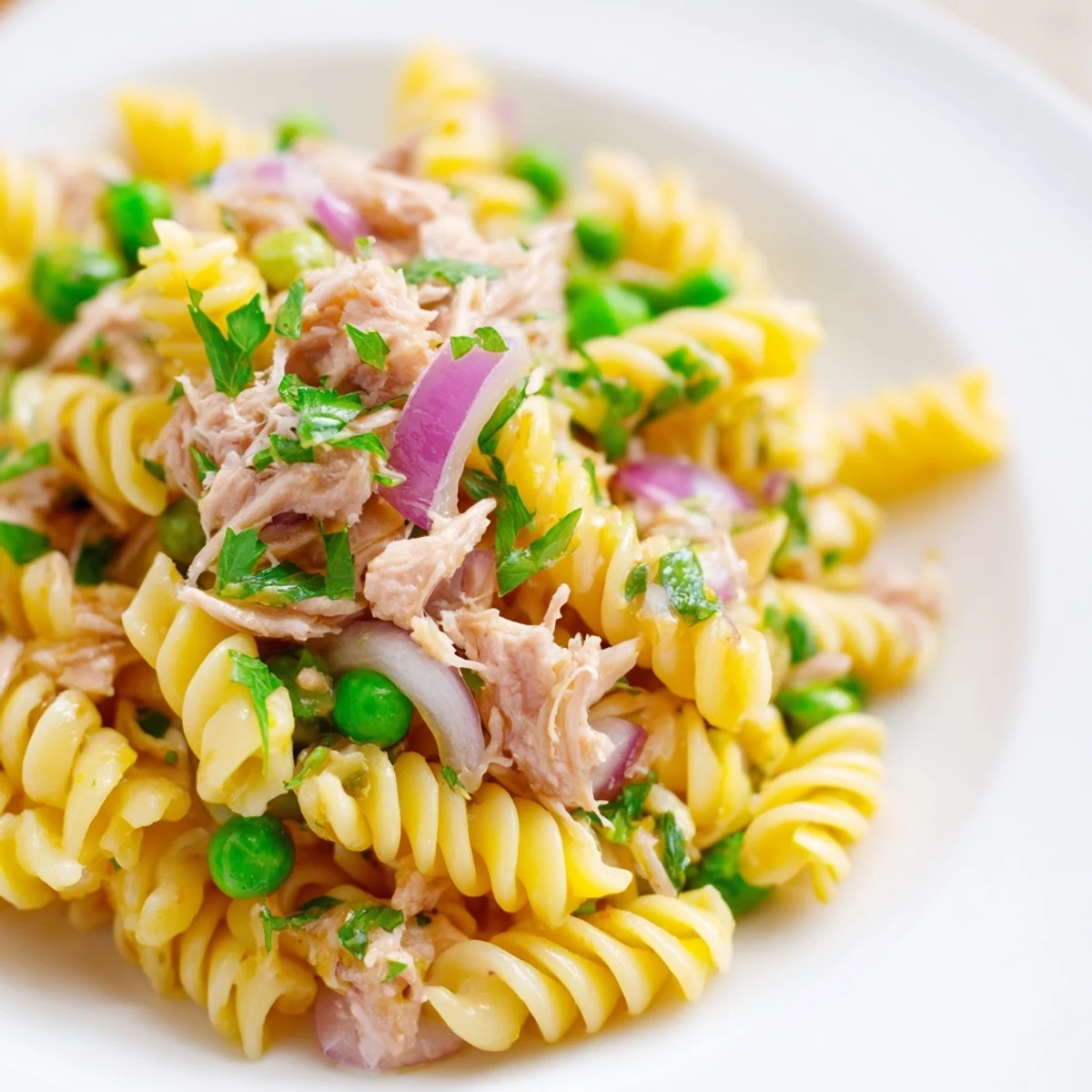 Bright and refreshing Lemony Tuna Pasta Salad with peas, herbs, and flaked tuna served on a white plate, ready for a light lunch.