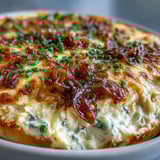 A spoon lifting a creamy scoop of Smoked Gouda & Onion Dip revealing melted cheese and caramelized onions.