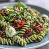 Fresh summer pasta salad with pesto, cherry tomatoes, and mozzarella—vibrant colors and creamy textures perfect for picnics or potlucks.