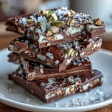 Decadent chocolate bark featuring golden kataifi pastry, pistachio cream, and rose petal garnish.