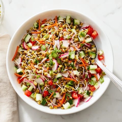 A vibrant bowl of Sprouted Seed Salad with fresh mung bean, alfalfa, and radish sprouts tossed with diced cucumber, tomato, and bell pepper.  