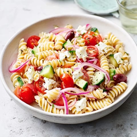 Creamy feta cheese complements the vibrant vegetables and zesty dressing of this Mediterranean pasta salad.