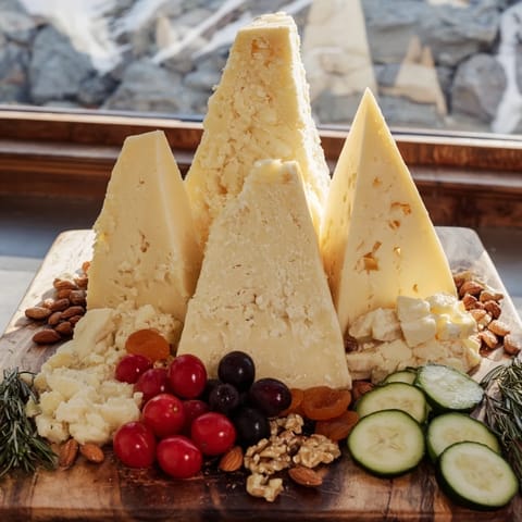A decadent Sculptural Cheese Landscape with grapes, nuts, and a drizzle of honey; a party appetizer.