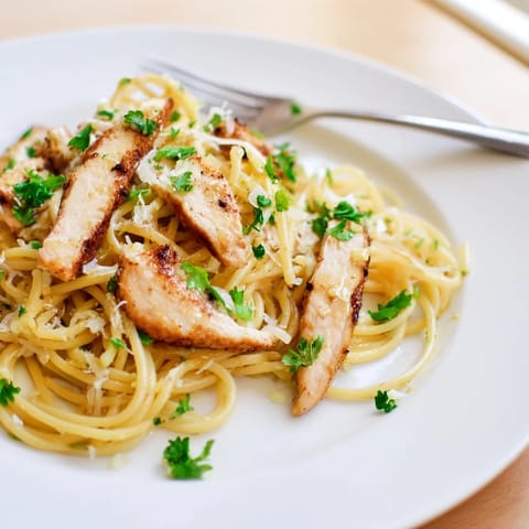 Steaming platter of Brown Butter Lemon Chicken Pasta topped with fresh parsley and lemon wedges, served as a hearty Italian-American weeknight meal.