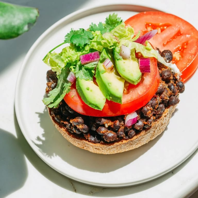A fully-assembled Zesty Weeknight Black Bean Burger with avocado, lettuce, and red onion on a toasted bun.
