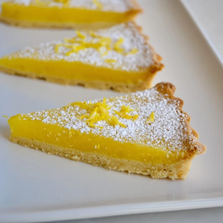 A close-up shot of bright and sweet lemon bars, freshly baked and cut into perfect triangles.