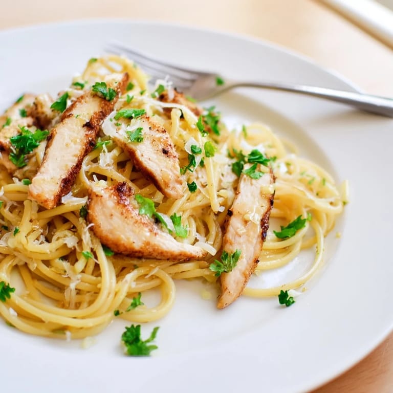 Steaming platter of Brown Butter Lemon Chicken Pasta topped with fresh parsley and lemon wedges, served as a hearty Italian-American weeknight meal.