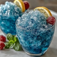 Blue Raspberry Lemonade Slushie with vibrant blue swirls, tangy citrus, and sweet raspberry flavor—perfect for a refreshing summer treat.